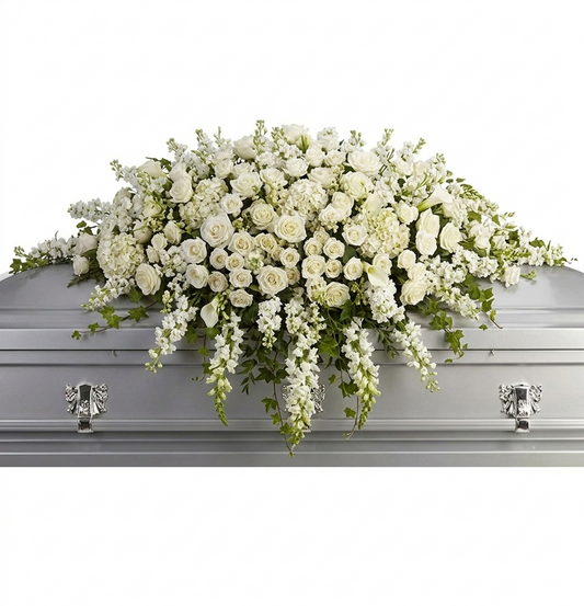 Premium white casket spray with white roses, spray roses, stock, calla lilies, hydrangea, and trailing greenery.